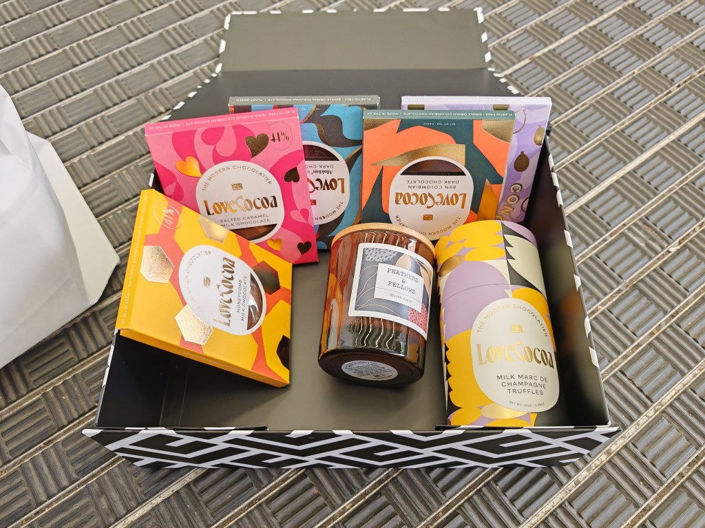 5 chocolate bars, a candle, and a tube of truffles in a gift box