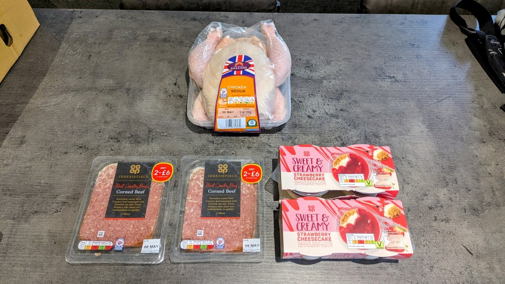 A whole raw chicken, with 2 packs of spam and two packs of strawberry cheesecake dessert underneath