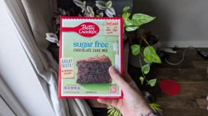 Betty Crocker sugar free cake mix box being held in front of some green plants