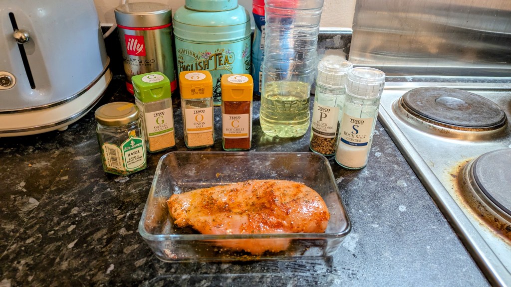 Seasoned chicken in an oven dish in front a collection of spices