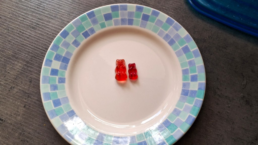 A vodka gummy bear next to a normal gummy bear on a plate