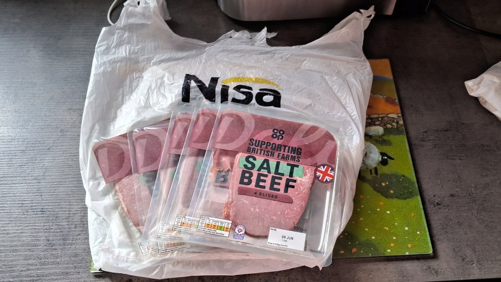 5 packets of salt beef slices on a Nisa carrier bag on a worktop