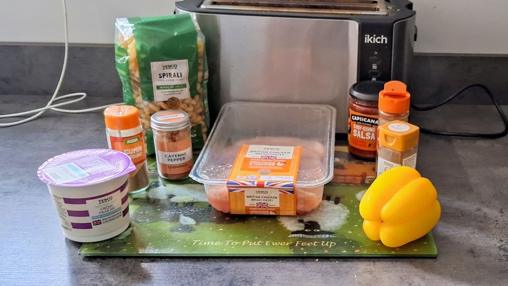 The ingredients for creamy cajun chicken pasta on a chopping board