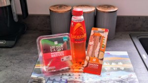 A Co-op meal deal of a sandwich, watermelon pieces, and a Lucozade on the worktop