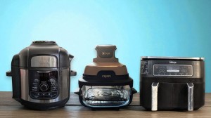 Ninja Foodi Max multicooker, Crispi, and Foodi Dual Drawer on a blue background with a wooden ledge