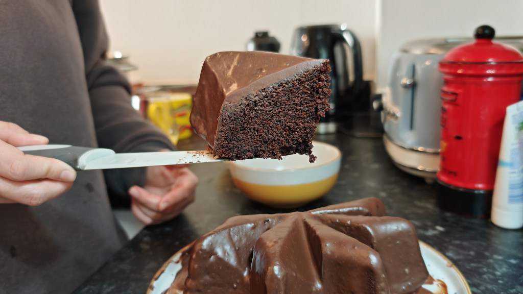 A slice of the chocolate cake covered with set dark chocolate ganache