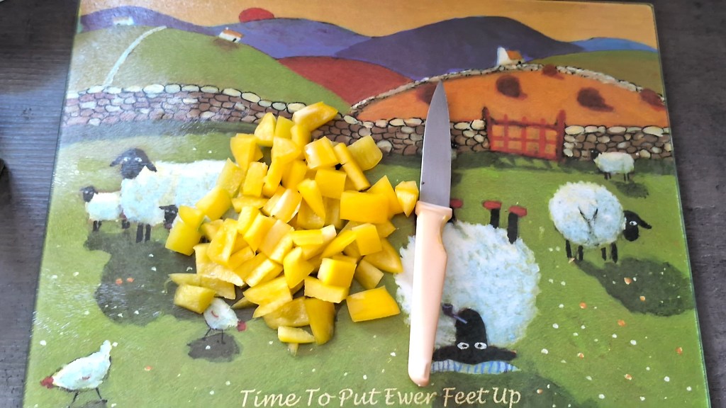 Chopped yellow pepper on a cartoon chopping board with a yellow handled knife